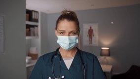 Caucasian female nurse wearing surgical mask and gloves standing in doctors office