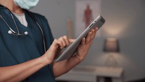 Close up caucasian female nurse standing in doctors office typing on digital tablet