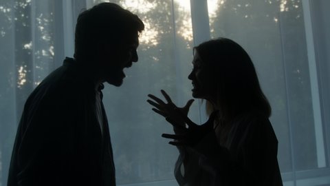 Silhouettes of man and woman shouting at each other, couple quarreling in the evening at home husband and wife screaming. Scandal and crisis in family. Domestic violence, abuse.