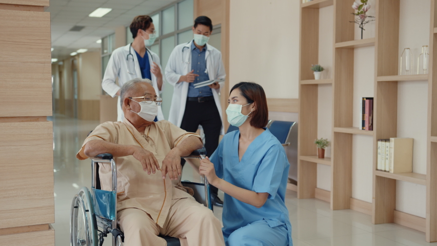 Young Asian woman nurse caregiver wear medical face mask encourage take care her patient explain information use wheelchair in hospital ward, Epidemic and virus, Hospital environment concept.