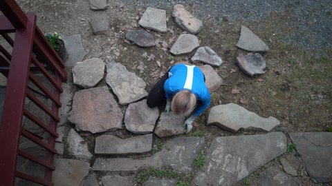 Overhead shot of mature woman setting rocks in place for patio walkway.
