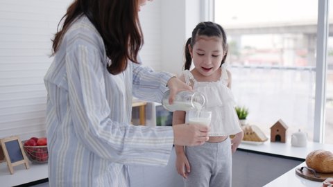 Mother and daughter happy to drink fresh milk in kitchen at home. Milk is beneficial for growth of body for children. family living together with love. Weekend activity happy family lifestyle concept