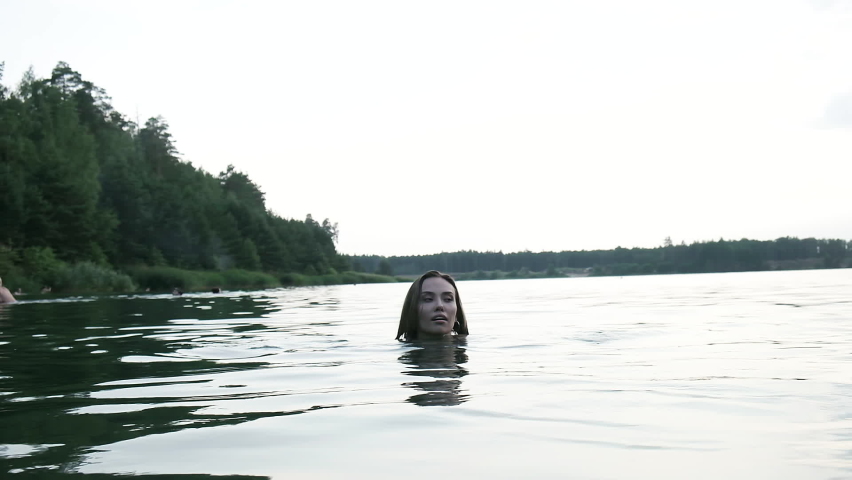 slim wet pretty female in bikini walking out of water after swimming in lake. fit asian woman in swimwear go out of river to beach in slow motion. summer chill, vacation, rest and pleasure at nature