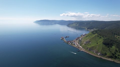 Lake Baikal is a marvelous blue jewel framed by scenic mountains and forests. Epic cinematic aerial view Lake Baikal. Aerial view of blue lake and green forests.