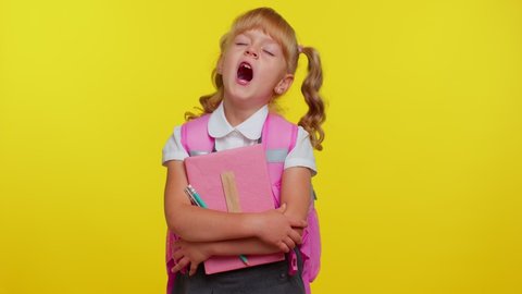 Pretty tired blond student girl dressed in school uniform yawning, sleepy inattentive feeling somnolent lazy bored gaping suffering from lack of sleep. Yellow studio background. Back to school