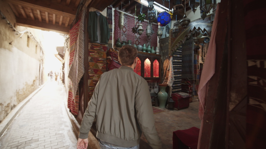 Back view of man walking through local shop with home decoration. Handmade traditional products. Morocco, Africa