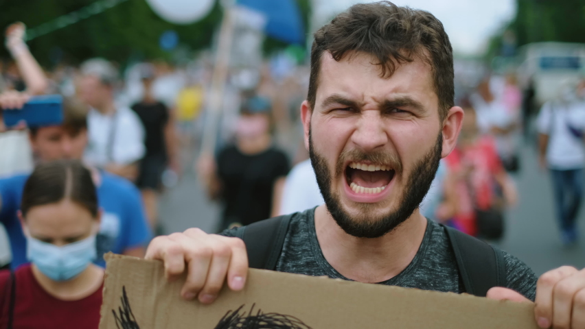 Angry protester people on political rally with placard sign shouts. Aggressive raging irritated activist person with demonstration banner protesting. Rebel man full of hatred on anti government strike Royalty-Free Stock Footage #1077722372