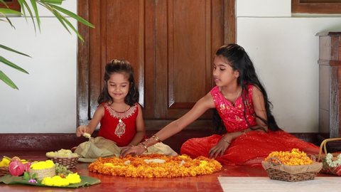 Onam Festival_ Girls making flower rangoli at veranda of a kerala traditional house.