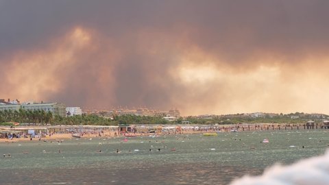 Flames and smoke from wildfires cover the landscape. Clouds of smoke over hotels and over the sea: Antalya, Manavgat Turkey - July 28, 2021.