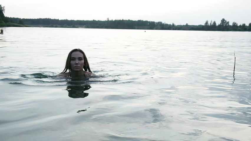 slim wet pretty female in bikini walking out of water after swimming in lake. fit asian woman in swimwear go out of river to beach in slow motion. summer chill, vacation, rest and pleasure at nature