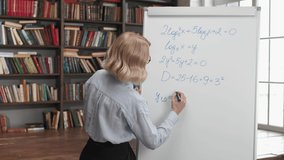 Online education by female teacher at university library interior. Woman writing on school board by marker. Distance video learning of math lesson for students. Casual life and internet home study