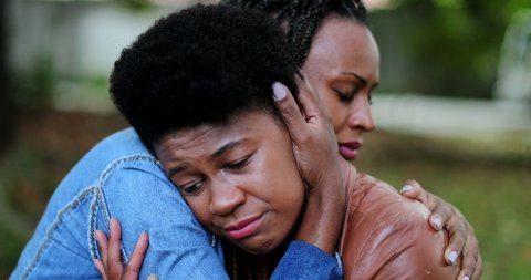 Depressed African woman, friend helping compassionate hug