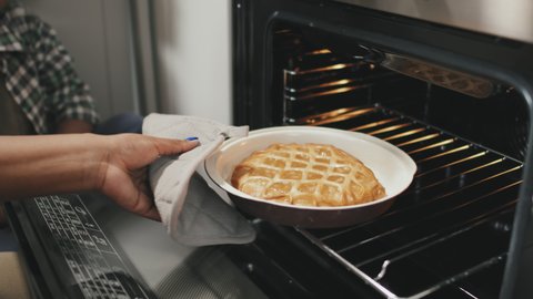 Slowmo close-up of unrecognizable African-American woman wearing kitchen mitten taking delicious homemade apple pie out of oven