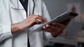 Mixed race male doctor typing on digital tablet 