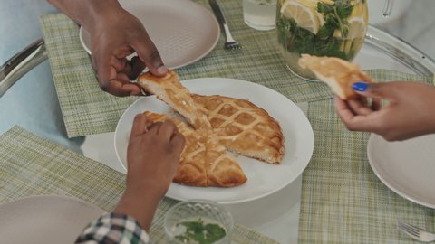 Slowmo close-up of three pairs of hands taking pieces of delicious homemade apple pie from dinner table