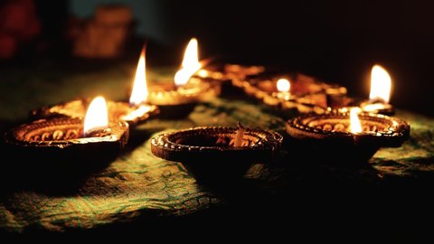 A Person rekindles beautiful Diwali Diya lamps with another glowing one. Beautiful oil lamps decorated on the occasion of Diwali, celebrated by Hindus also known as the festival of lights.
