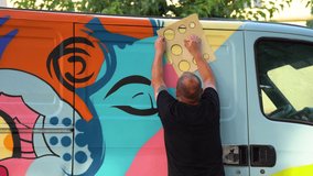 graffiti artist preparing stencil for painting van