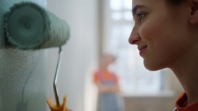 Happy woman moving paint roller on wall in new home. Smiling girl painting inside new house. Joyful female painter working in new apartment during home repair.  - Powered by Shutterstock - Get 15% off with code: PIKWIZARD15