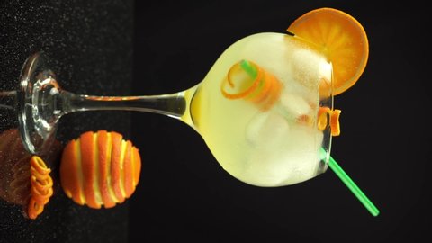 A hand preparing gin orange cocktail with ice, 4k vertical video, close up