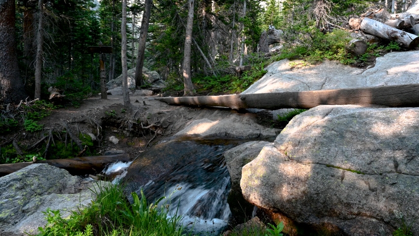 Hiking across the log bridge over Andrews Creek on the Sky Pond trail in Rocky Mountain National Park, Colorado, USA