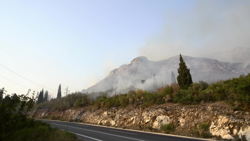 Smoke from forest fires in the mountains over an asphalt road