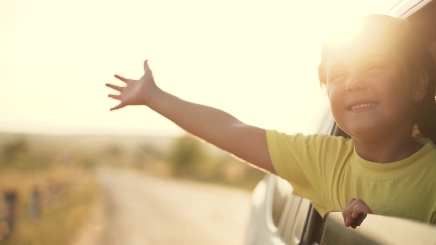 Child in car window. Family car trip. Child hair in wind. Girl looks out of car window. Happy child travel with his family. Girl stretches out his hand to wind. Happy family travel concept by car | Shutterstock HD Video #1077778190