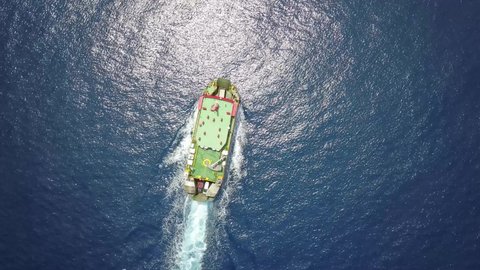 Ferry on the sea, transporting cars: deck of a boat carrying vehicles. Summer sun reflecting off the rippled water surface of lake or river revealing waves texture. Aerial top view from a drone