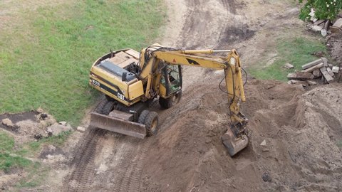 excavator work at a construction site, top view. powerful machine hydraulic reverse bucket Caterpillar (CAT) digs the ground. 
August 18, Kyiv, Ukraine