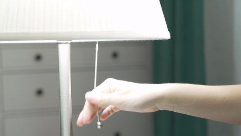 Female Hand Turns On The Lamp, Turns On The Light. Female Hand Pulls the String and the Light Turns On, A closeup of the Lamp, the Ropes and the Hands.