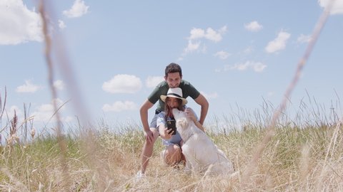 Happy couple with dog taking selfie in field