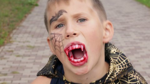 Vampire Halloween boy. Teenager bares false fangs painted with fake blood 