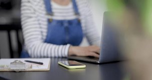 Woman sitting at desk taking smartphone, close-up