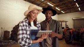 Caucasian female farmer holding digital tablet while mixed race male points around shed room