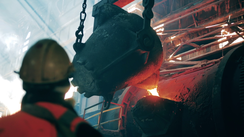 Steelmaker, metallurgist, metalworker at the metallurgical factory. Pouring of melted metal done under control of a steel worker | Shutterstock HD Video #1077790775
