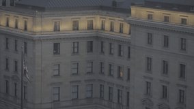 An American federal building at dusk, one can see some lighting over it and an American flag is flapping by, a 4K (S-Log) video clip, Cleveland OH, United States.