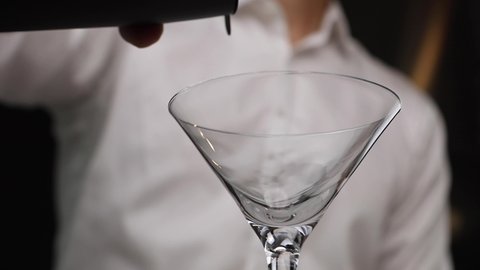 Bartender pouring martini on glass RAW