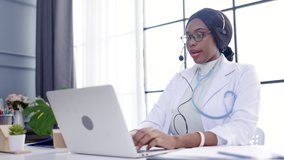African American doctor wearing headset In hospital Video calling service talk to distant patients. Medical consultation. meeting webinar with colleagues. tele health and telemedicine concept. 