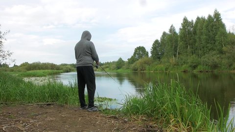 man fishing near the river bank in summer weather