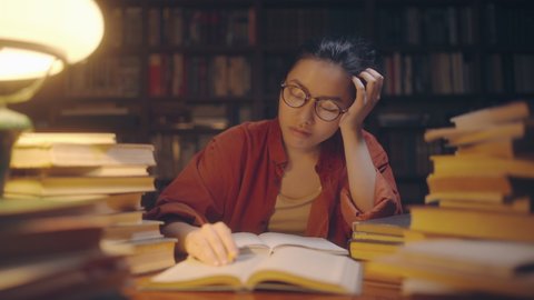 Exhausted medical student falling asleep while working on project at library