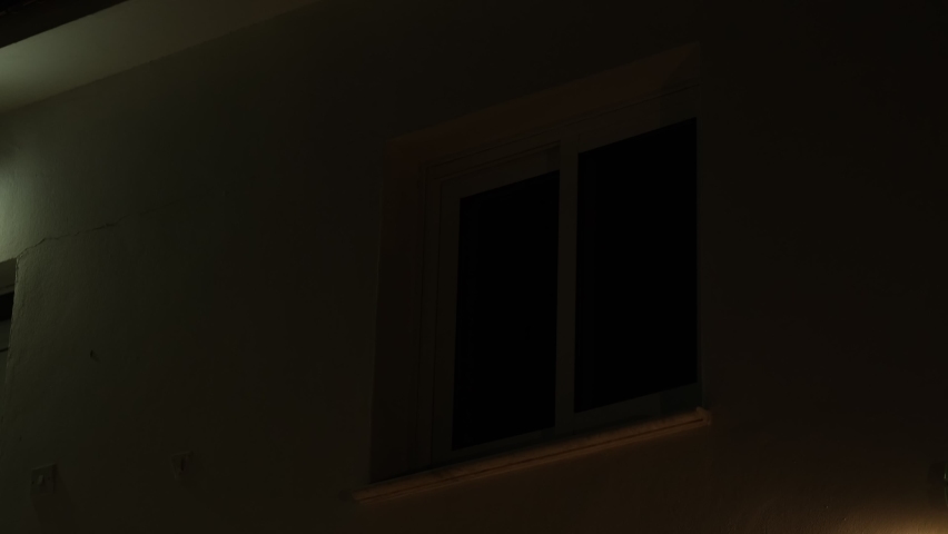 Light from the window of the house in the dark evening time. room lights up then turns off. Royalty-Free Stock Footage #1077810407