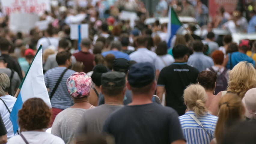 Protest people crowd on political riot in Russia marching on city streets, peaceful non-violent demonstration rally. Crowded protesters march with banners, placards, posters and signs on picket strike Royalty-Free Stock Footage #1077811241