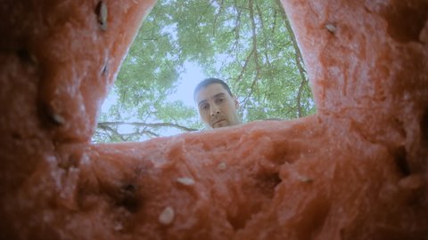 The guy cuts off a piece of watermelon with a knife and immediately eats it , enjoying the taste. A large berry. Melons. GoPro.