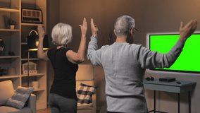elderly old couple physical exercise online in front of green screen chroma key television,senior man and woman workout at home