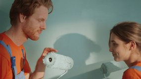 Cheerful man smearing woman nose with paint indoors. Playful couple painting wall together in new house. Joyful family doing decoration work in new apartment. - Powered by Shutterstock - Get 15% off with code: PIKWIZARD15