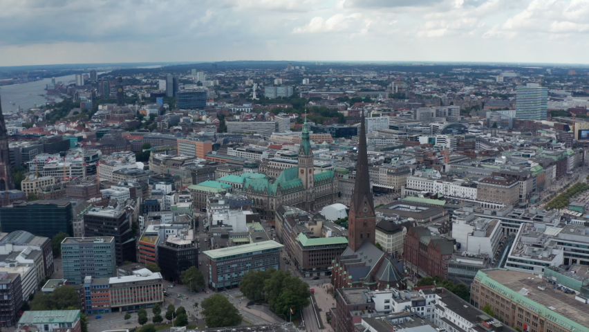 Aerial view of historic city centre with tall towers of city hall and churches. Harbour cranes in background. Free and Hanseatic City of Hamburg, Germany