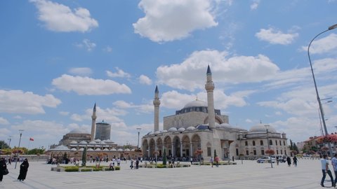 Sultan Selim Mosque (cami) and Mevlana tomb (turbe) in Konya, Turkey and beautiful and colorful flowers and many people and tourists  with blue and cloudy sky backgrounds.24.07.2021. Konya. Turkey