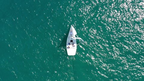 Yacht sailing on opened sea. Sailing boat. Yacht from drone. Aerial video. Sailboat from drone. Yachting at windy day. Open sea. small sailing boats during competition on blue cloudy sky background.