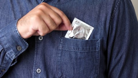 The young man took the condom out of his pocket. Campaign for safe sex and contraception. Close up male hand holding the condom.