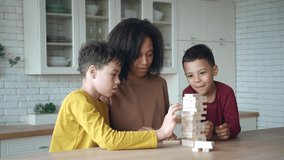 African American mom with kids playing board game, laughing after high toy wooden blocks tower falling. Family spending time together at home. Enjoying educational games during lockdown or day off - Powered by Shutterstock - Get 15% off with code: PIKWIZARD15