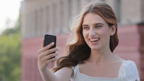 Attractive blonde blue-eyed millennial lady in summer dress record videoblog. Emotional young European Caucasian woman wave hand greets friends, share news, make online stream, video event concept